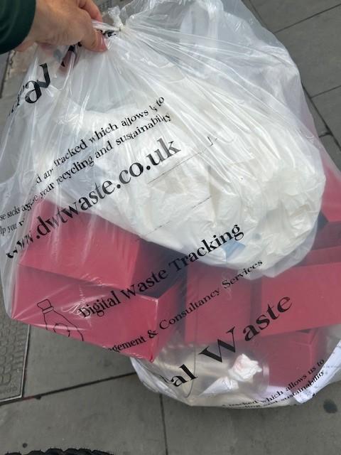 A DWT branded tracked waste sack being carried to the van